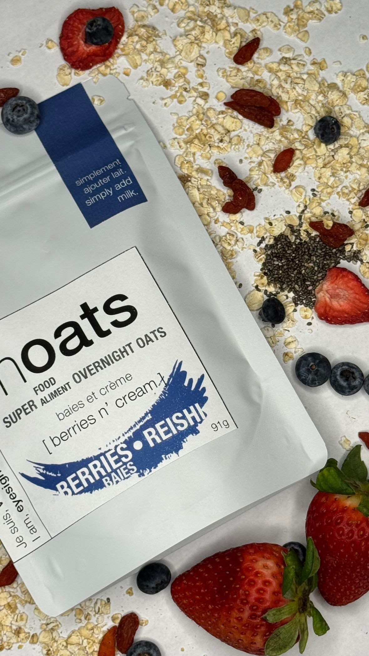 Berries n Cream Overnight Oats pouch with fresh blueberries and goji berries scattered on white background