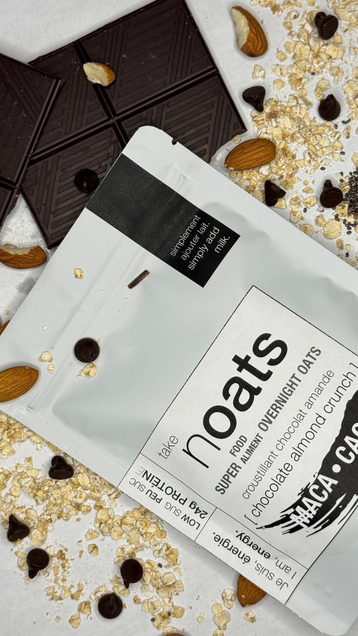 Chocolate Almond Crunch Overnight Oats pouch with dark chocolate bar pieces, almonds and rolled oats scattered on white background