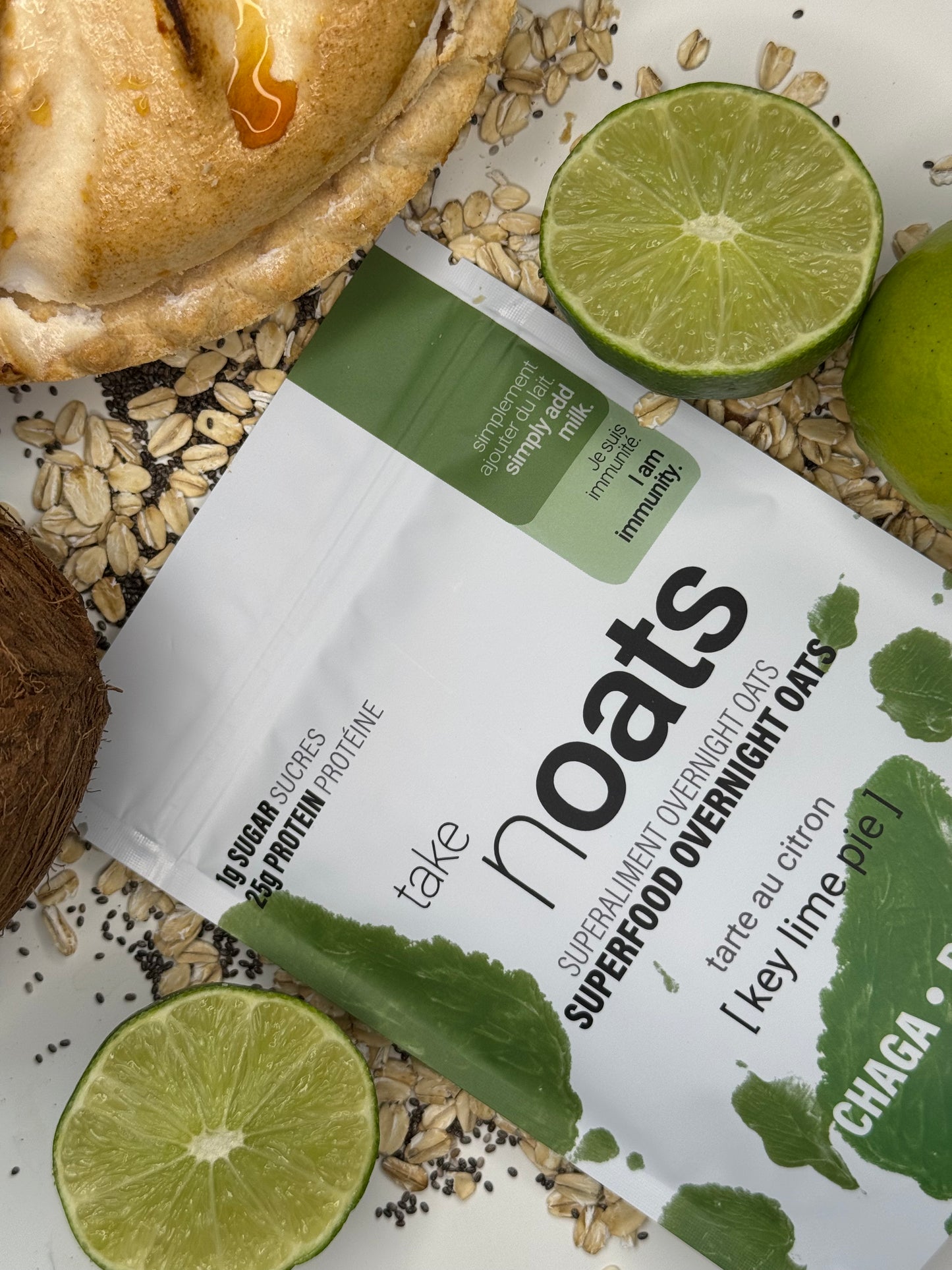 Key Lime Pie Overnight Oats pouch with lime wedges and rolled oats scattered on white background.
